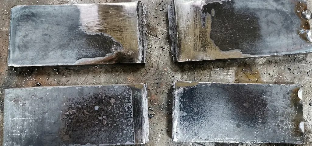 Cuatro probetas de doblado guiado ensayadas sobre una mesa de trabajo